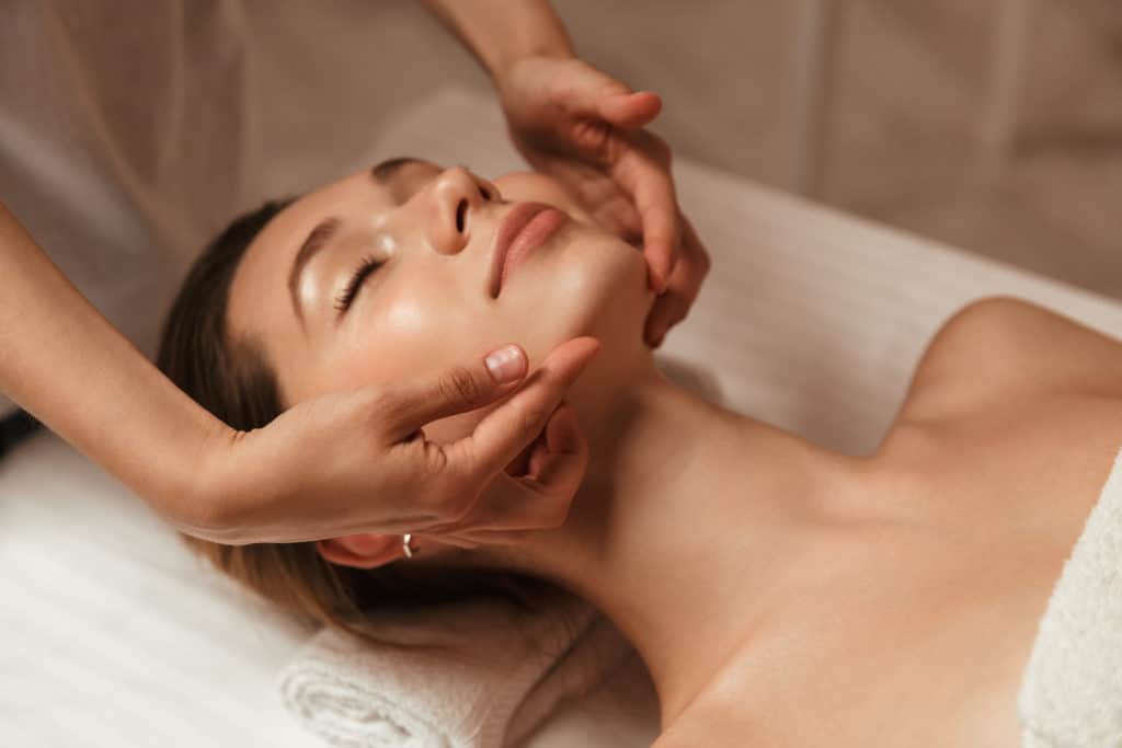 Young woman getting spa treatment with facial massage at a spa center | Adam J Cohen, MD in Glenview & Chicago, IL