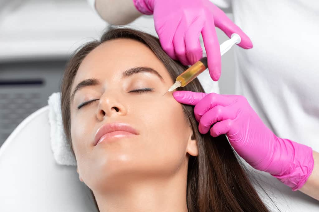 Beautician doing PRP therapy for the face against wrinkles and against hair loss of a beautiful woman in beauty salon. Doctor holds test tubes with venous blood and blood plasma. Cosmetology concept | Adam J Cohen, MD in Glenview & Chicago, IL