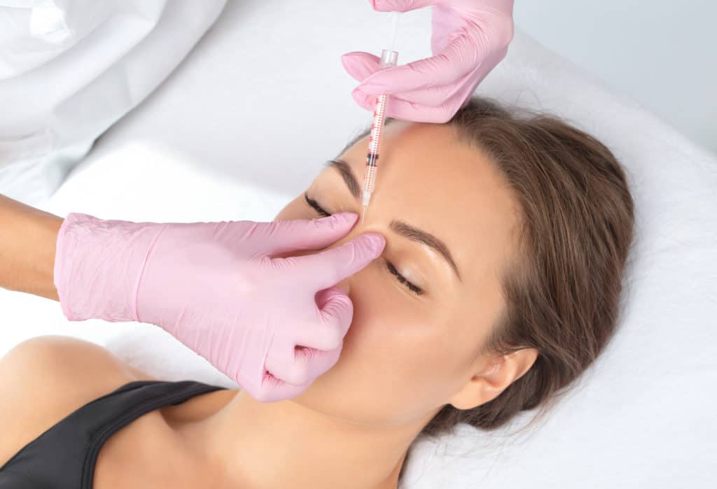 Cosmetologist makes rejuvenating anti wrinkle injections on the face of a beautiful woman. Female aesthetic cosmetology in a beauty salon | Adam J Cohen, MD in Glenview & Chicago, IL