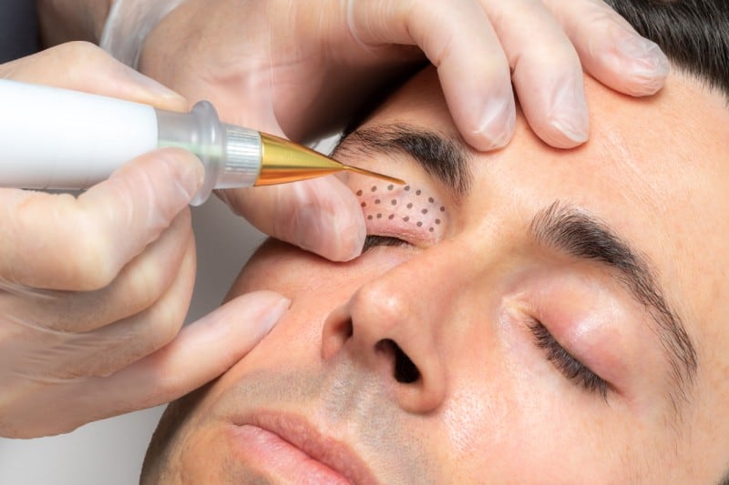 a person applying a tattoo on a man's face